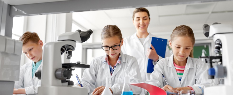 A group of children in lab coats collaborating on a science project, showcasing teamwork and curiosity in a laboratory setting.