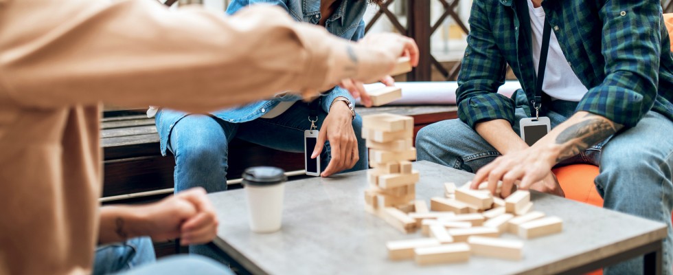 A group of individuals engaged in play with wooden blocks in a sunny outdoor environment, fostering creativity and teamwork.