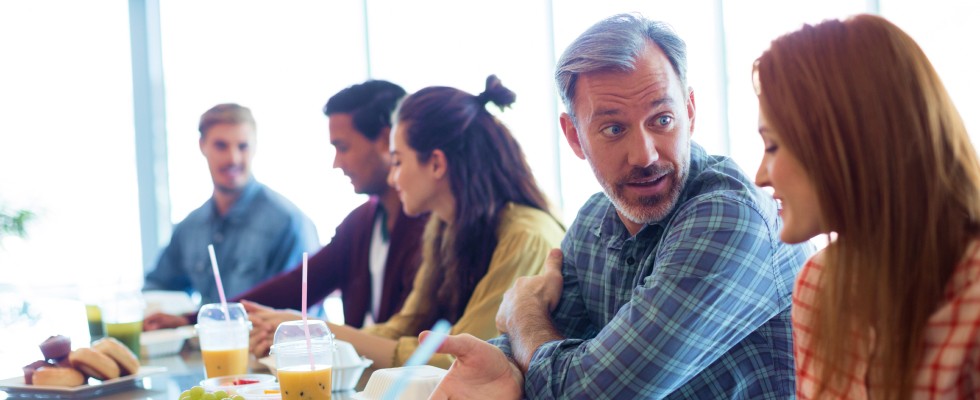 A diverse group of individuals gathered around a table, enjoying a meal together.