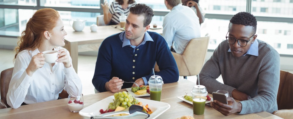 Three people enjoying a meal together at a table, with a variety of delicious food and refreshing drinks.