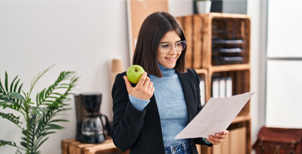 Woman holding an apple, reading a document.