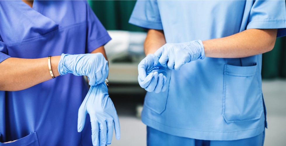 Two nurses wearing blue scrubs and gloves, engaged in a medical task, showcasing professionalism and care in healthcare.