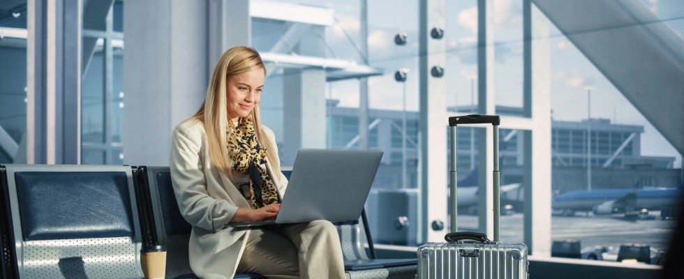 A woman on an airport lounge bench with a laptop, engaged in work or leisure.