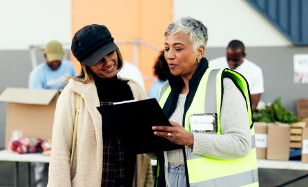 Two women look over a clipboard, showcasing organization and team efforts.