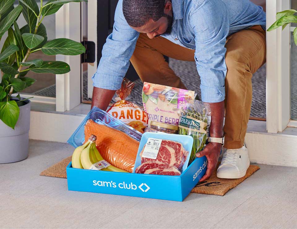 A Sam's Club member picks up a tray of neatly packed products in a delivery order from their doorstep.