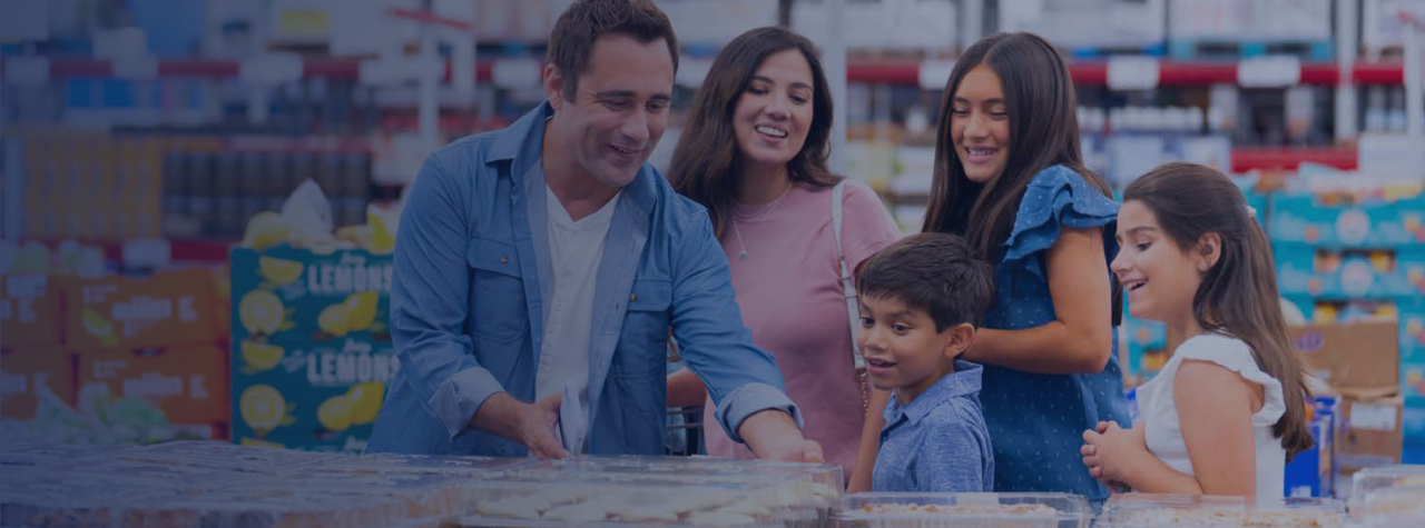 A family examines the shelves of items in a Sam's Club.