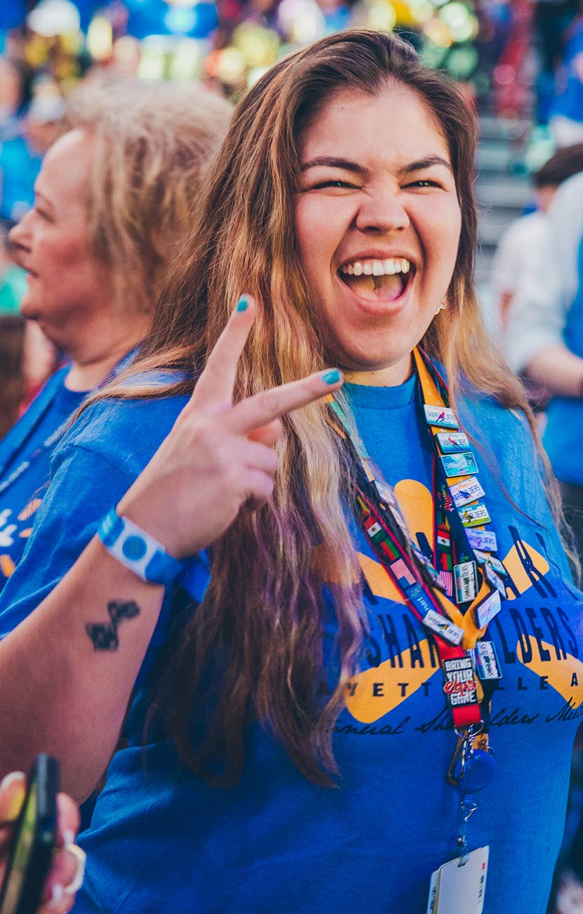 A Walmart associate smiles, flashing a peace sign in the Bud Walton Arena in Fayetteville, Arkansas, at Associates Week 2024.