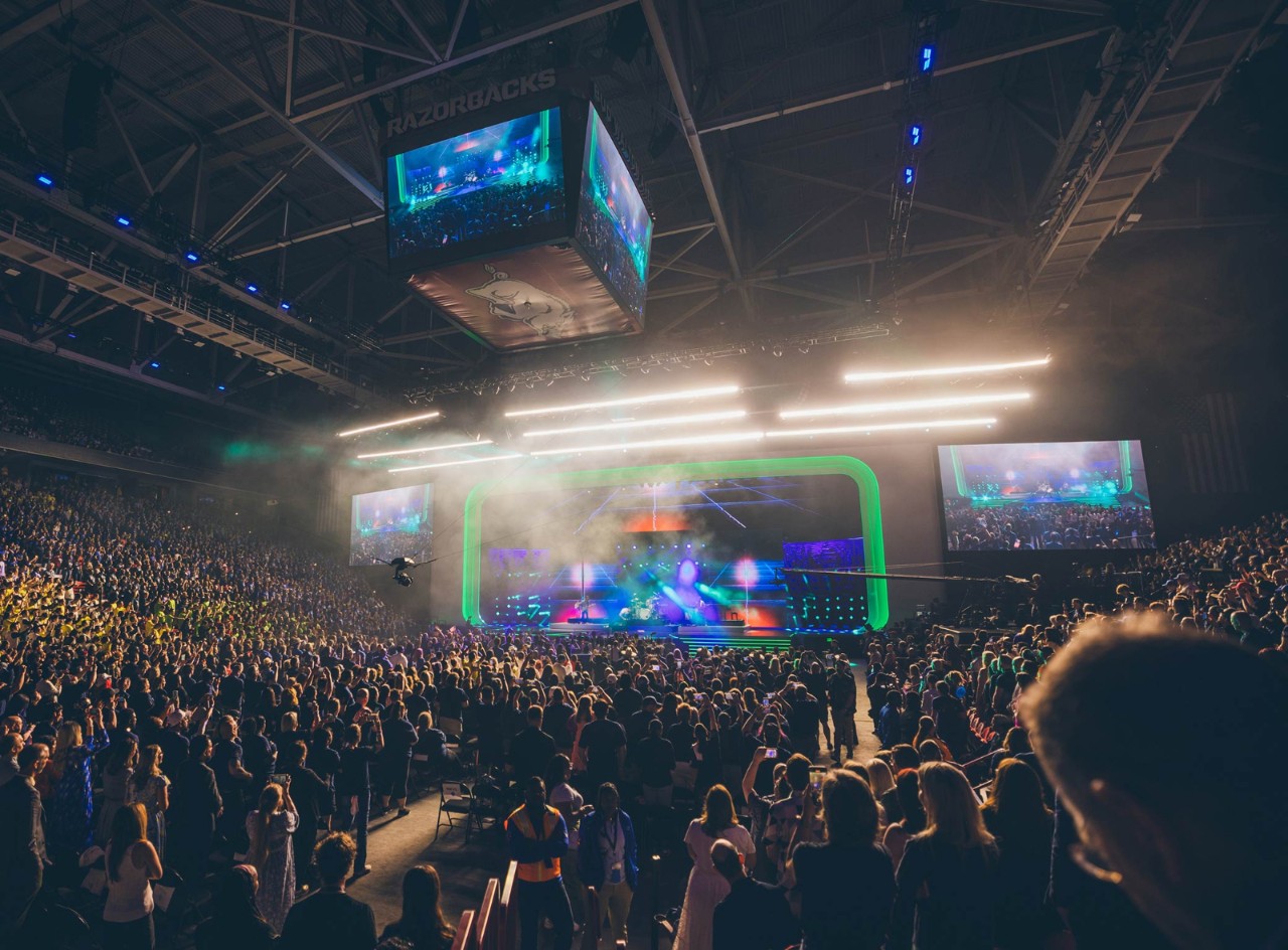 Thousands of Walmart and Sam’s Club associates face a colorfully lit stage in the Bud Walton Arena in Fayetteville, Arkansas.