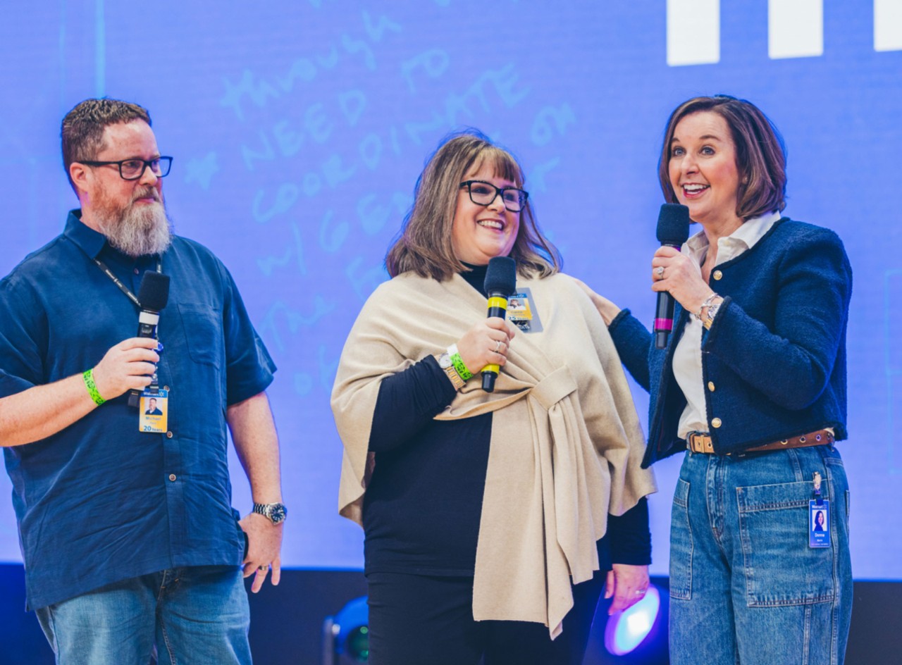 Associate Carrie Paris celebrates 25 years at Walmart during the January 2025 Morning Meeting. She stands next to her husband, Michael, and is introduced by Chief People Officer Donna Morris.