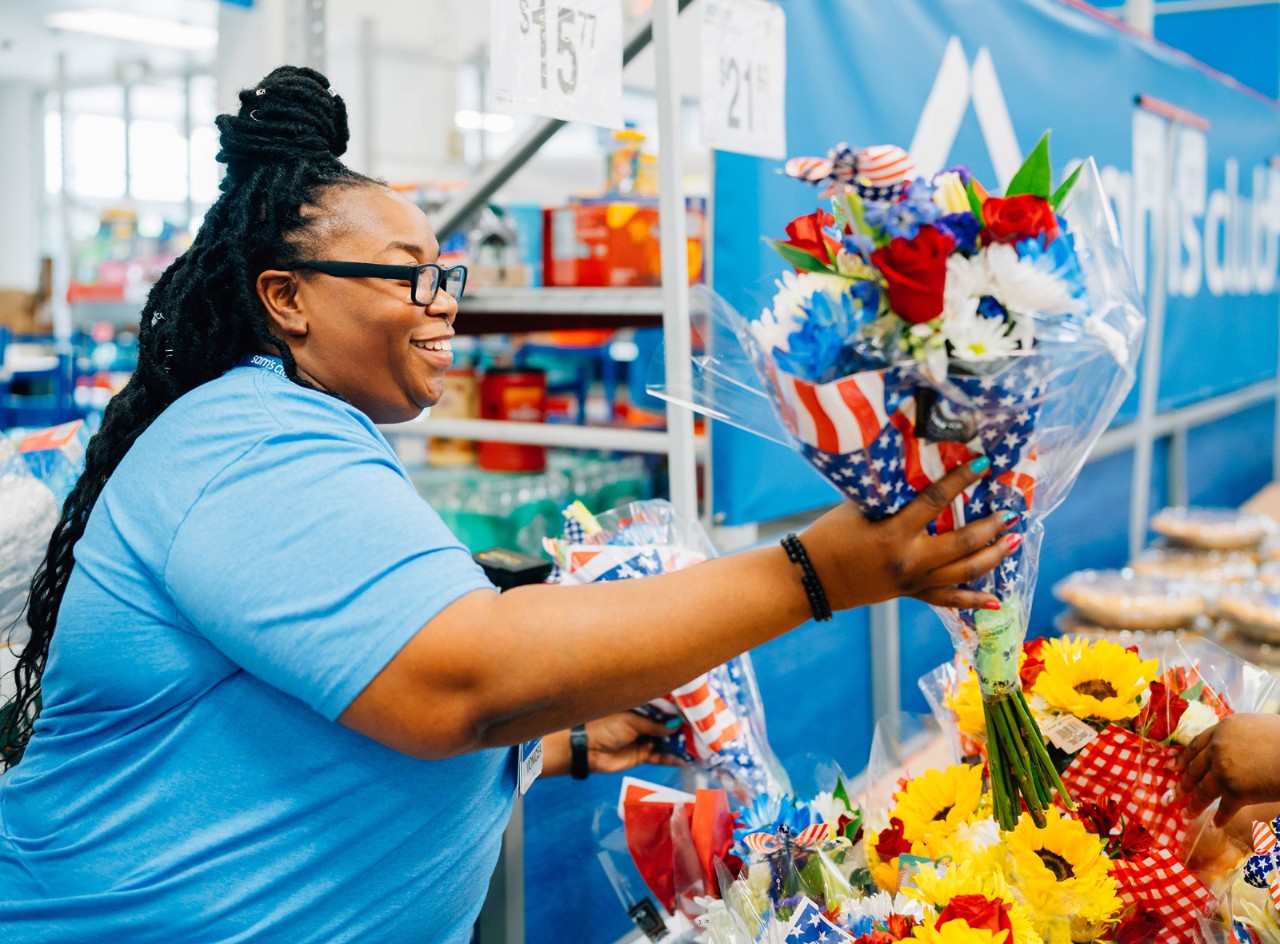 Sam’s Club associate Monicea Smith is shown passing a bouquet of flowers to a person off camera.