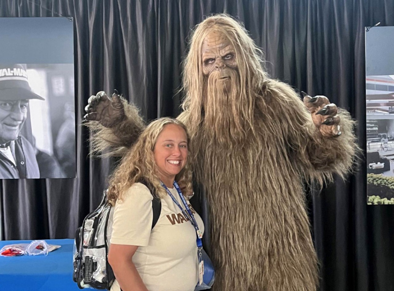 Amber smiles with a life-sized statue of Bigfoot at Associates Week 2024.