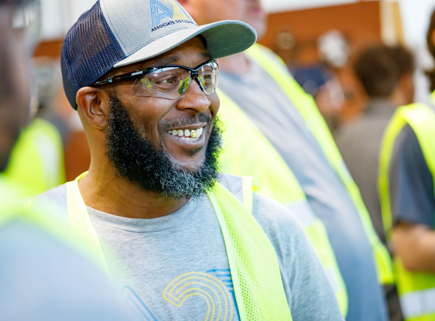 Hurk wears a ballcap with the Walmar A2T logo and smiles during class with other associates.