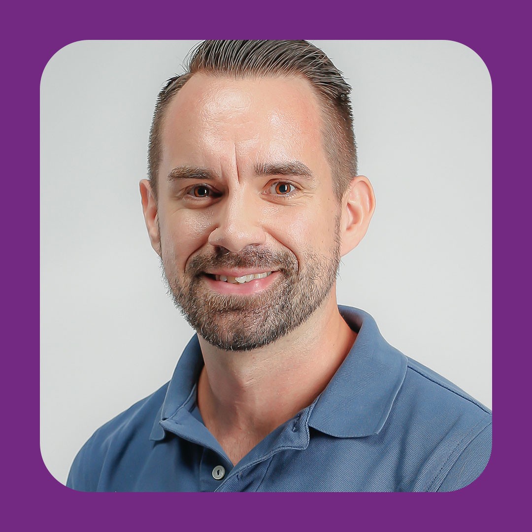 Walmart associate with short hair and beard smiles at camera.