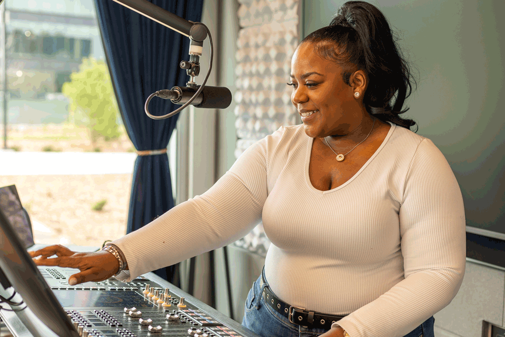 DJ Kirby Gwen stands at the soundboard in the Walmart Radio studio.
